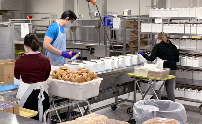 The Centerplate staff assemble bagels and juice into boxes.