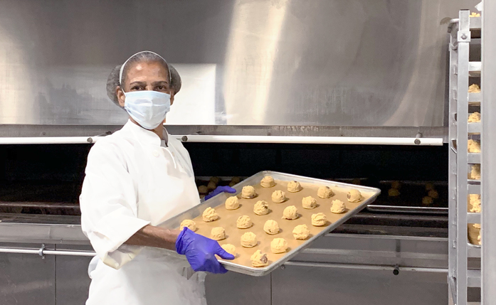 Centerplate staff member Bernitta Green puts cookies in the catering oven