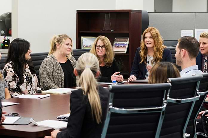 Dorianne sits in the middle of a table with her colleagues.