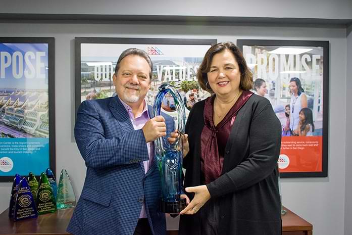 Karen Totaro and CEO Rip Rippetoe stand with a large trophy.