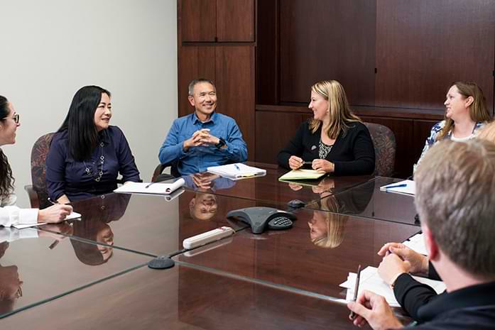 Mardeen is second from the right at a table with her colleagues.