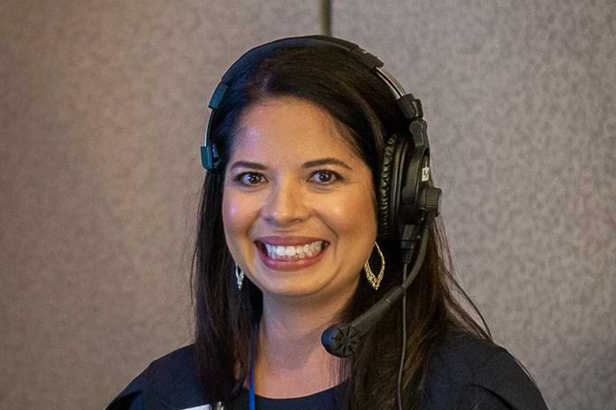 Rita smiles with large headphones on her head.