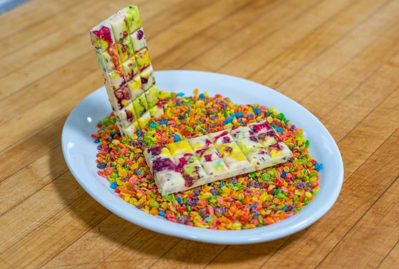 Photo of the white chocolate bar with  bright colors from the Fruitty Pebbles and freeze dried raspberries